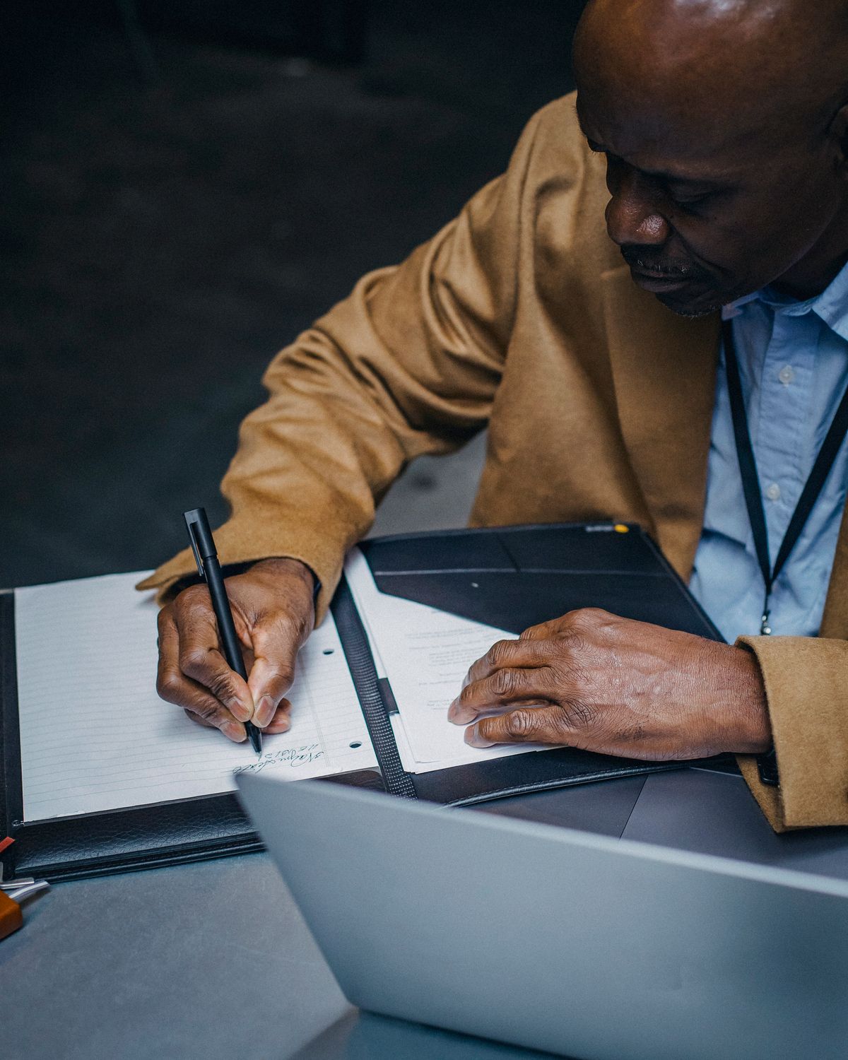 Senior analyst annotating written notes beside a laptop
